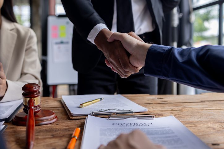 People shaking hands after signing a contract agreement.
